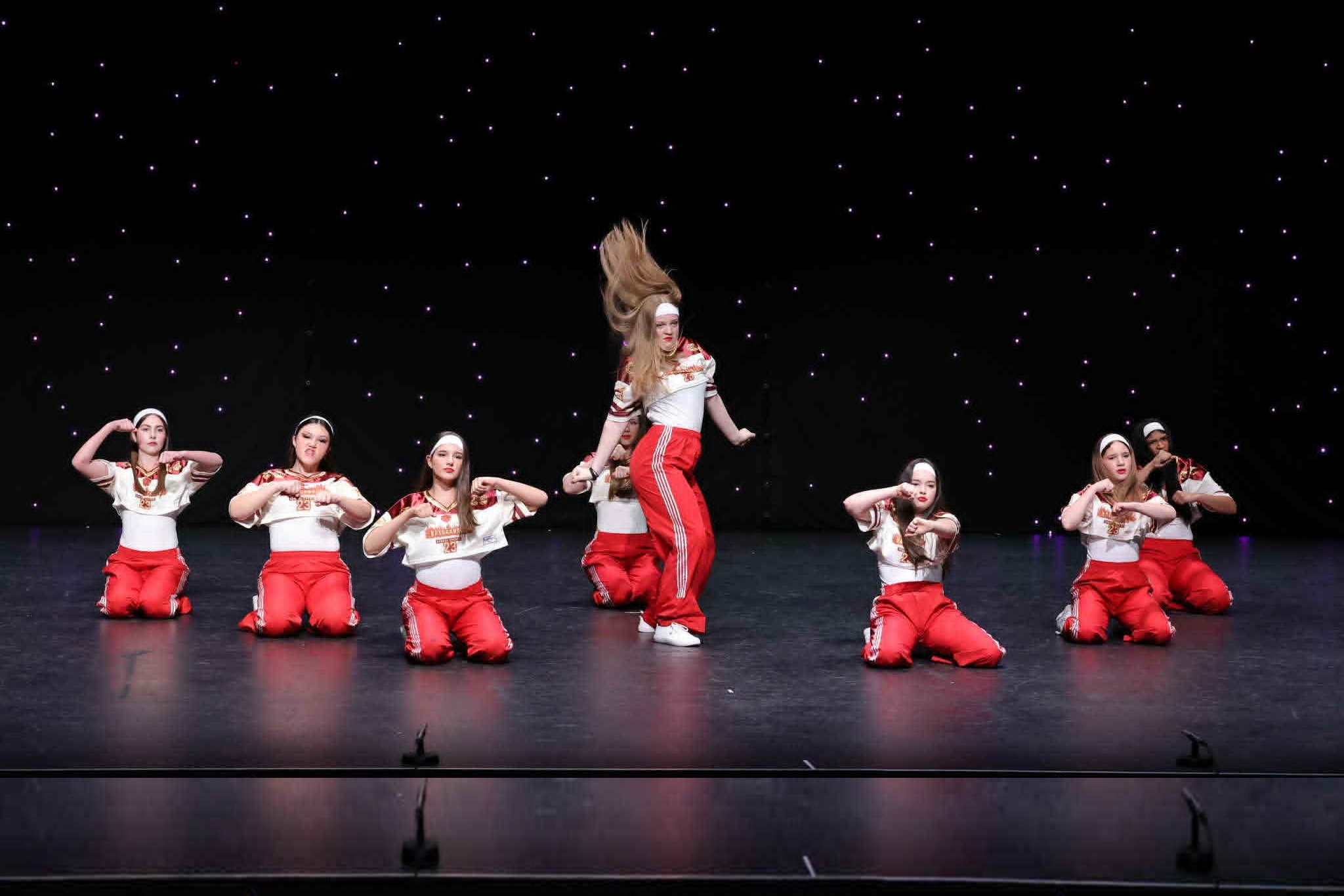 Stage Door Academy hip hop students performing on stage in red and white costumes.